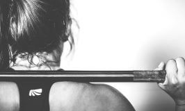 A black and white photo of a woman lifting a barbell.
